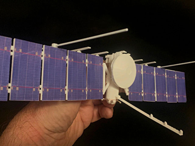 hand holding a 3D-printed model of the Europa Clipper spacecraft