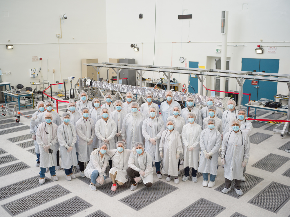 The ECM team seen in Europa Clipper's High Bay 2, with the spacecraft's magnetometer boom deployed in the background. 