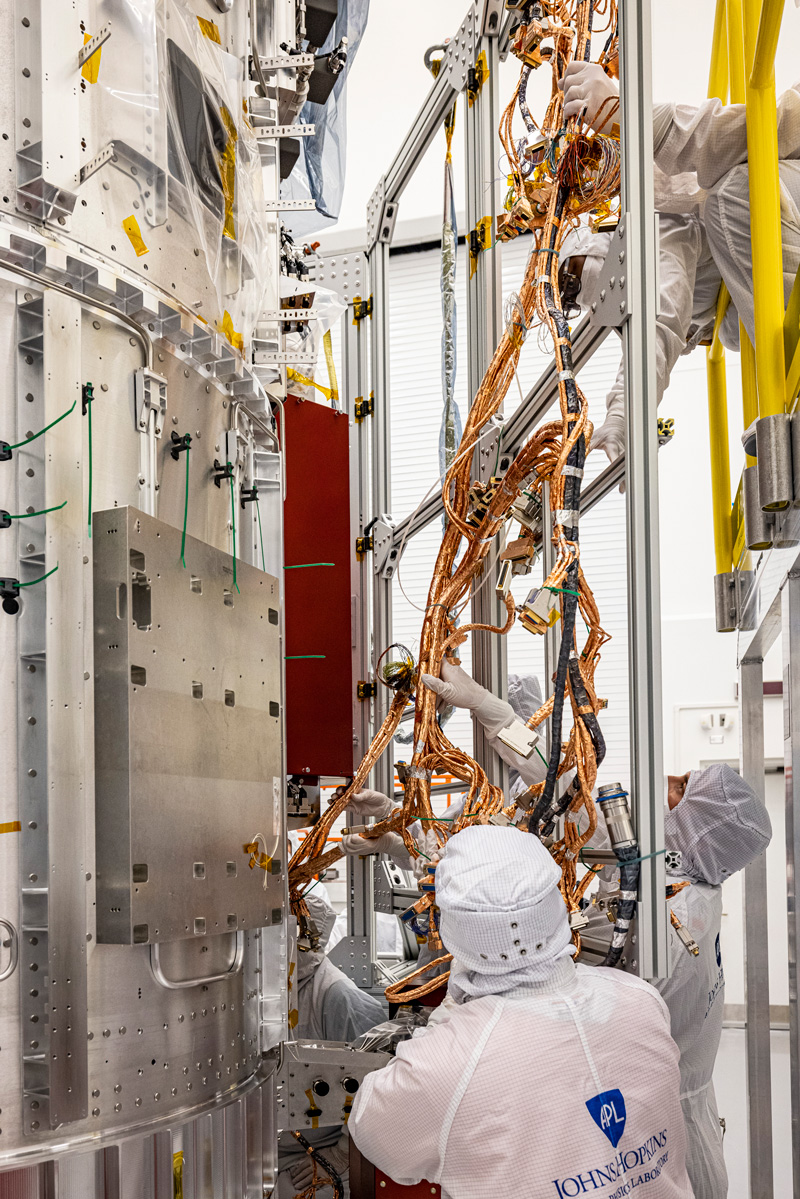 in the clean room, people work on the spacecraft's electronics