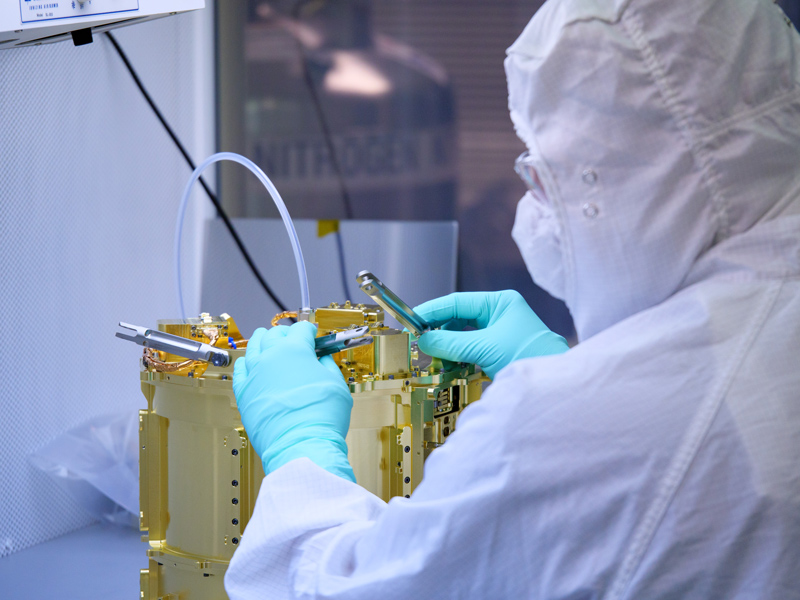 An image showing an engineer prepares to integrate the SUrface Dust Analyzer (SUDA)'s sensor head with an ion detector at the Laboratory for Atmospheric and Space Physics (LASP) at the University of Colorado Boulder. The sensor head will detect and determine the mass of ion molecules generated by impacting dust particles.