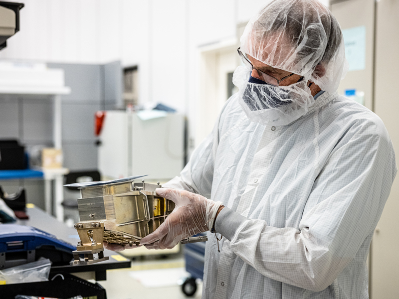 Instrument designer and lead scientist Philip Christensen stands in a white bunny suit 