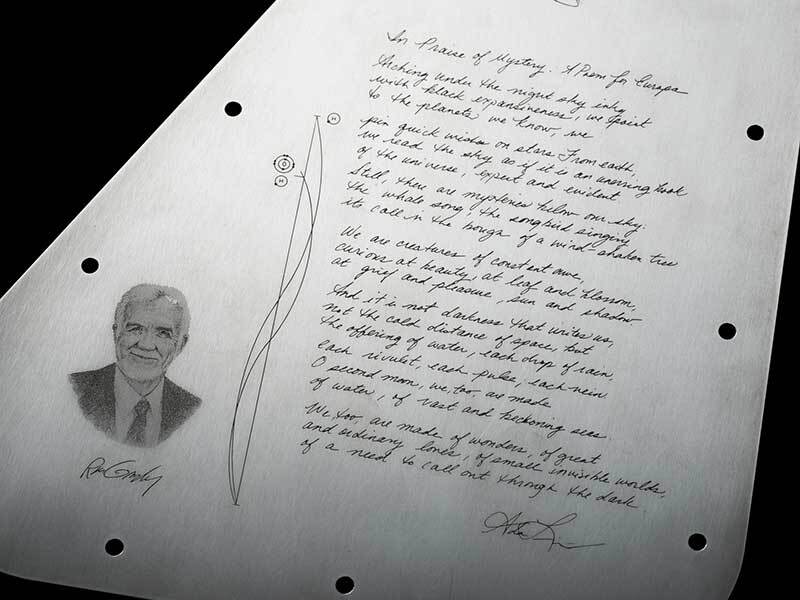 This is a close-up view of the poem on the Europa Clipper vault plate’s inward-facing side. It shows a handwritten poem in elegant script, and an engraved portrait of man to the left of the poem.
