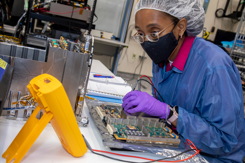 Image showing Southwest Research Institute (SwRI) Staff Engineer Yvette Tyler performs integration and testing on the electronics box for Europa Clipper’s mass spectrometer. The mass spectrometer will analyze gases in Europa’s faint atmosphere and possible plumes. It will study the chemistry of the moon’s suspected subsurface ocean, how ocean and surface exchange material, and how radiation alters compounds on the moon’s surface. Credit: NASA/SwRI 