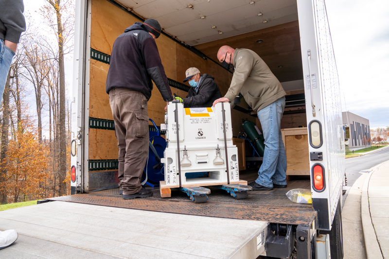 Members of Europa Clipper’s imaging spectrometer instrument, called MISE, team at the Johns Hopkins Applied Physics Laboratory place a container loading the instrument’s scanning mirror and data processing unit on a shipping truck. The truck transported the instrument parts to NASA’s Jet Propulsion Laboratory in Pasadena, California, in November 2021. 