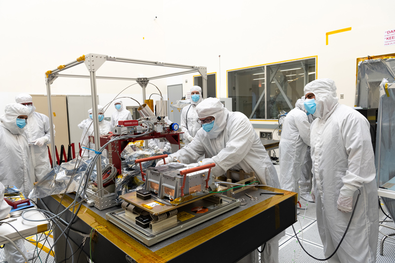 Image showing engineers inspecting the spacecraft's ultraviolet spectrograph in a cleanroom. 