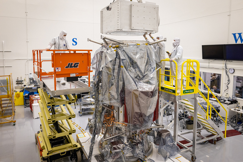 Engineers integrate the avionics vault mass simulator for the Europa Clipper avionics module to the top of the propulsion module.